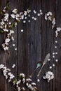 Old dark rustic wooden table surface with white spring blossom flowers and antique silver dishware