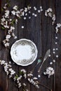 Old dark rustic wooden table surface with white spring blossom flowers and antique silver dishware