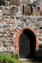 Old dark wooden door in stone wall. Royalty Free Stock Photo