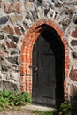 Old dark wooden door in stone wall. Royalty Free Stock Photo