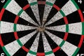 Old dartboard punctured by darts on light wall. Background of an old shabby round target in holes and cuts for game of darts Royalty Free Stock Photo