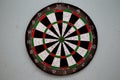 Old dartboard punctured by darts on light wall. Background of an old shabby round target in holes and cuts for game of darts Royalty Free Stock Photo