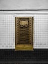 Old decorative brass metal door on a background of black and white wall with ceramic tiles. Decorative metal door on the track Royalty Free Stock Photo