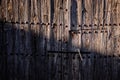 Old and decrepit wooden gate, half lit by the sun, in an unpopulated rural area