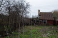 An old, decrepit wooden house with a rusty, broken roof and an overgrown garden, illustrating neglect and decay