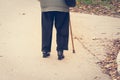 Old depressed woman walk alone down the street with walking stick or cane feeling lonely and lost view from back