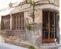 Old derelict abandoned commercial property on a corner with crumbling cracked shabby walls and rusting iron bars across the door