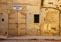 Old and derelict doors set in a crumbling limestone wall in Sliema, Malta