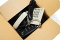 Old desk phones in a cardboard box.