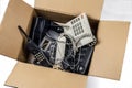 Old desk phones in a cardboard box.