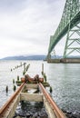 Old destroyed trolley for loading and unloading ship cargo and the remains of a wooden pier on the background of a bridge in Royalty Free Stock Photo
