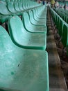 Old, deteriorated, empty green seats in a sports stadium