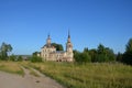 An old dilapidated church overgrown with trees in the countryside against a blue sky with clouds surrounded by greenery Royalty Free Stock Photo