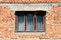 Old dilapidated house window with cracked faded wooden frame on red brick wall Royalty Free Stock Photo