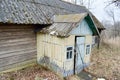 The old dilapidated porch, the entrance to the wooden village house and the wall of dilapidated logs of an abandoned village house Royalty Free Stock Photo