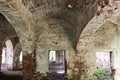 Old dilapidated red brick building. The room inside with vaults of crumbling brick. Wide walls, large openings of windows and Royalty Free Stock Photo