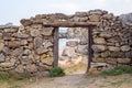 An old dilapidated stone wall with a doorway overlooking the sea and the rocky shore. Film decoration Royalty Free Stock Photo