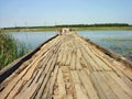 An old dilapidated wooden bridge is laid across a small quiet river. Royalty Free Stock Photo