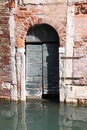 old dilapidated wooden door in a brick facade inundated by a Venice canal