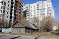 An old dilapidated wooden house stands against the background of a new high-rise building