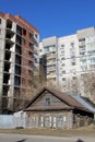 An old dilapidated wooden house stands against the background of a new high-rise building