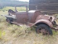 Old dilapidated 1920& x27;s roadster in front of a mining cabin