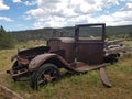 Old dilapidated 1920& x27;s roadster in front of a mining cabin