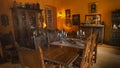 Old dining room decorated with wooden furniture old paintings and chandeliers illuminated with yellow light