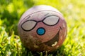 Old dirty ball with happy funny face on grass at sunny daylight.