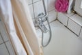 Old dirty bathtub, shower curtain, and faucet in an apartment bathroom. Top view, white faience wall, no people