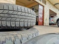 Old and dirty car tires stacked in a car mechanics shop ready to be changed and repaired by the mechanical professionals