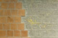 Old dirty damaged wall with brown orange ceramic tiles and gray cement with yellow paint stains. rough surface texture Royalty Free Stock Photo