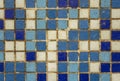 Old dirty damaged wall with white blue violet small square ceramic tiles. rough surface texture