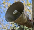 An old, dirty, grey loudspeaker is mounted on a pole. In the background, there is a blurred image of the sky and tree branches Royalty Free Stock Photo
