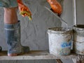 Old dirty grungy bucket on a wooden stand, being used for cement plastering by a construction worker