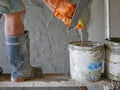 Old dirty grungy bucket on a wooden stand, being used for cement plastering by a construction worker