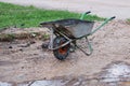 An old dirty metal wheelbarrow with an orange wheel. Used construction tool, side view. Agricultural Wheel Farm Cart Royalty Free Stock Photo