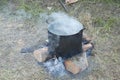 Old fashioned cooking stove with metal steel pans on a fire. Cooking food by scout at camping scout . the water evaporates from Royalty Free Stock Photo