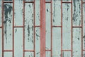 An old dirty pale green oil painted window glass closed by a burgundy metal grate. Grunge background.