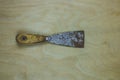 Old dirty and rusty putty knife isolated on wooden background