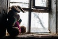 Old dirty stuffed toy rabbit on windowsill in abandoned house