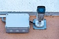 An old dirty surveillance camera, covered with dust and cobwebs, installed on the facade of the building in close-up. Security and Royalty Free Stock Photo