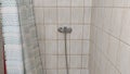 Old dirty tiled bathroom with shower and dirty floor in a cheap hostel or student dormitory Royalty Free Stock Photo