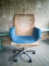 Old dirty vintage armchair covered with a blue rag against a rough concrete wall Royalty Free Stock Photo