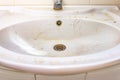 Old dirty washbasin with rust stains, limescale and soap stains in the bathroom with a faucet, water tap