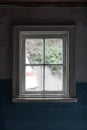 Old dirty white wooden window of an abandoned dark 19th century house. View from the inside
