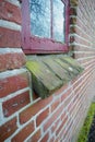 Old dirty window on a brick wall house or home. Ancient casement with red wood frame on a historic building with a Royalty Free Stock Photo