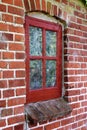 Old dirty window in a brick wall house or home. Ancient casement with red wood frame on a historic building with a Royalty Free Stock Photo