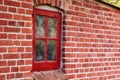 Old dirty window in a red brick house or home. Ancient casement with red wood frame on a historic building with clumpy