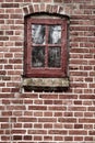 Old dirty window in a red brick house or home. Ancient casement with red wood frame on a historic building with clumpy Royalty Free Stock Photo